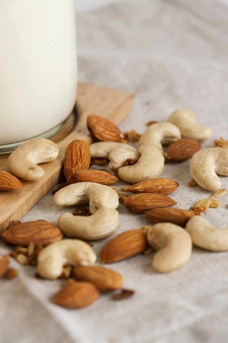 Amandes et noix de cajou posées au pied d'une bouteille de boisson végétale