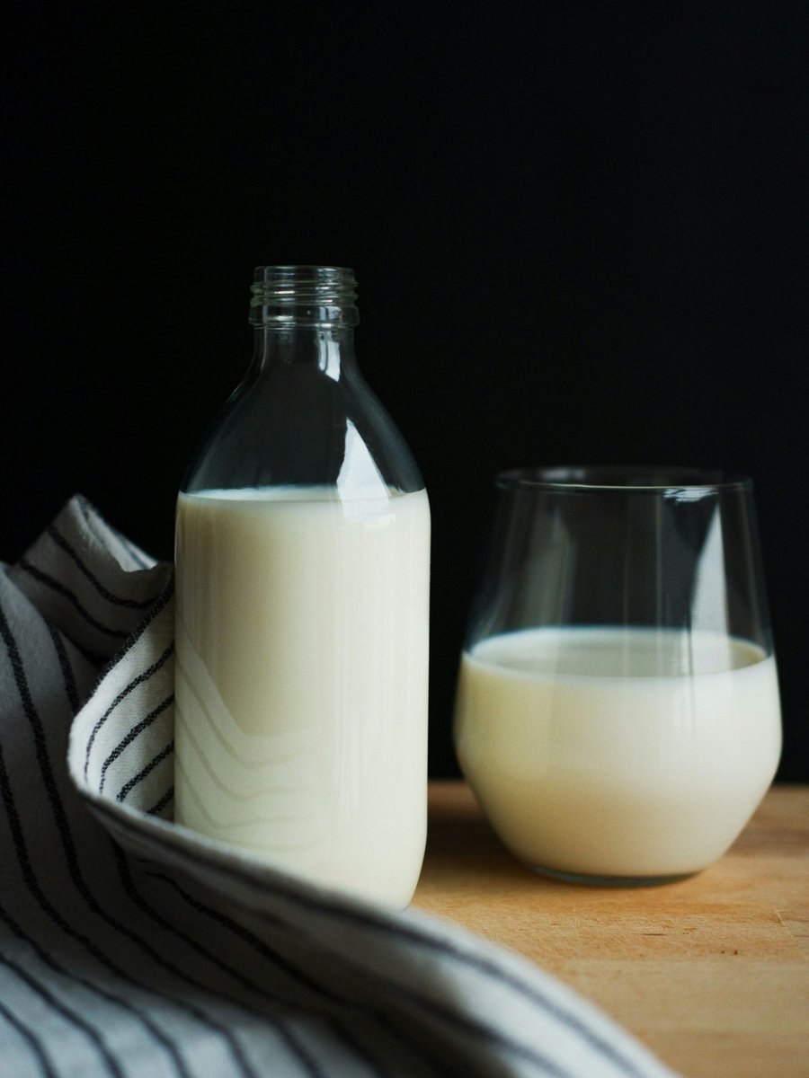 Bouteille et verre de boisson blanche posés sur une table, torchon rayé