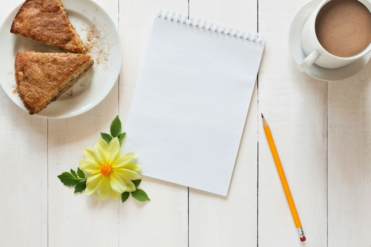Bloc-notes, crayon, café et part de gâteau sur une table blanche
