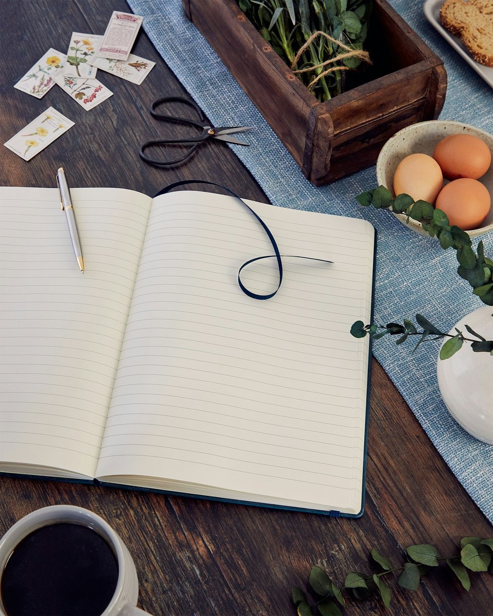 Carnet ouvert, stylo, œufs et tasse de café sur une table en bois