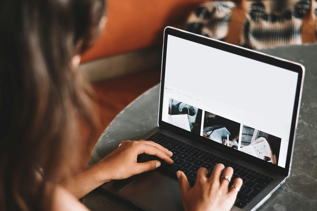 Mains posées sur le clavier d'un ordinateur portable, visage hors cadre