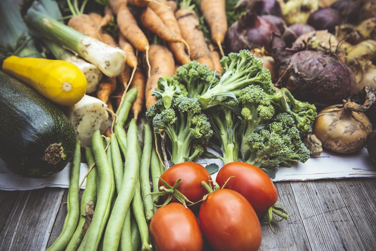 Haricots verts, tomates, brocoli, courgette et racines sur une table en bois
