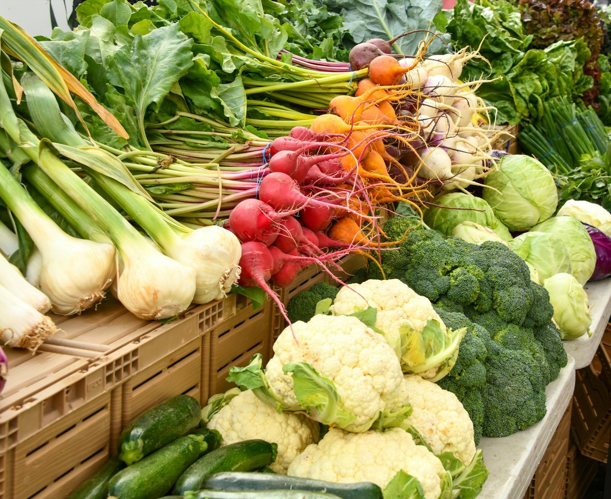 Étal de marché avec choux-fleurs, brocolis, radis et oignons nouveaux