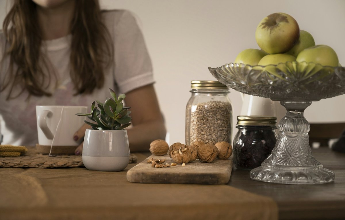 Ordinateur ouvert sur une table de cuisine, à côté de fruits et de bocaux