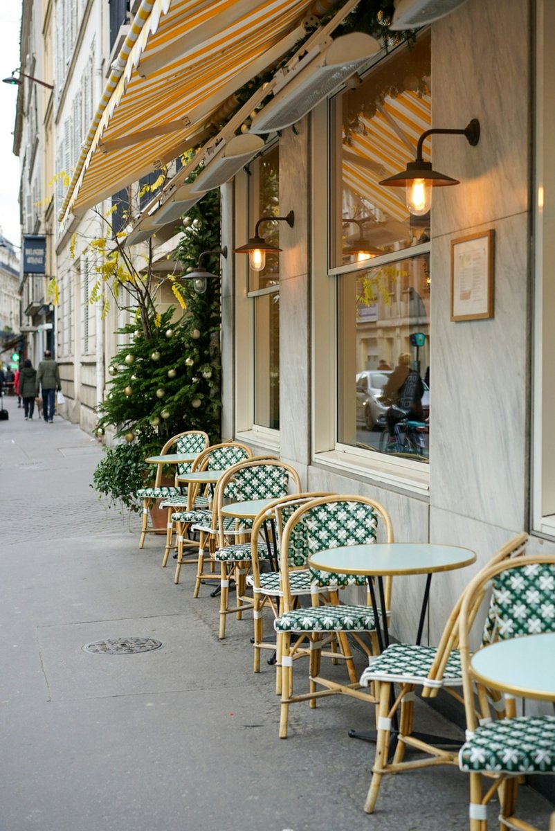 Terrasse de café parisien vide, chaises cannées et tables rondes